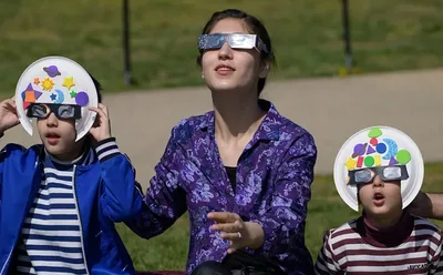 People watching a solar eclipse wearing certified eclipse glasses