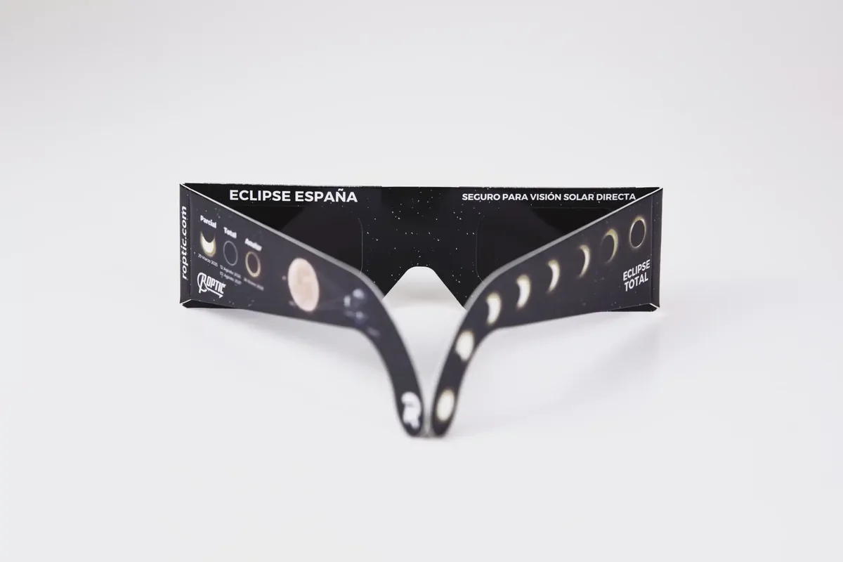 ROPTIC eclipse glasses face-on on a white background, printed with “Eclipse España · Safe for direct solar viewing” and the eclipse sequence on the temple